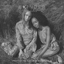 Cargar imagen en el visor de la galería, a black and white image of two women looking elegantly radiant and content sitting in a field
