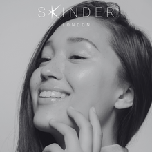 Carica l&#39;immagine nel visualizzatore di Gallery, a soft black and white image of a young woman with clear, bright, even radiant, glowing skin. the SKINDER LONDON logo is at the top of the image. this image denotes top beauty trends, optimum skin hydration. @skinderofficial
